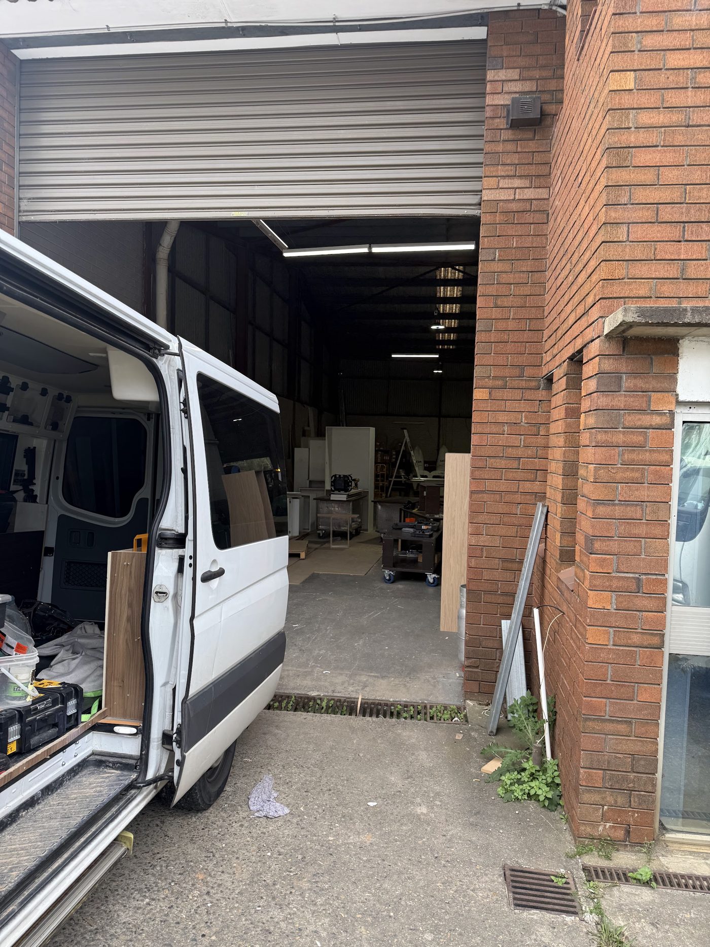 The roller door of the Forge Street unit, with a work van loaded with board and tools and the workshop behind