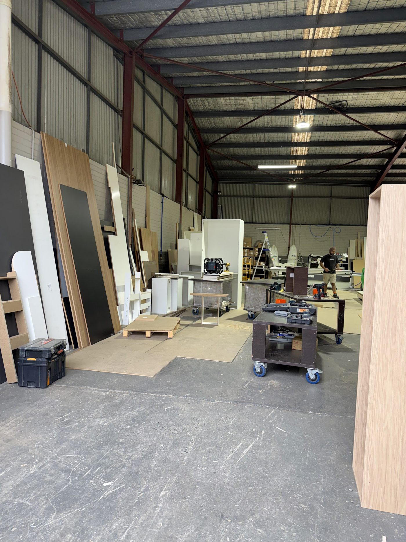 Inside the Modern Joinery and Kitchens workshop: racks of white, oak and black board, workbenches and panel machinery